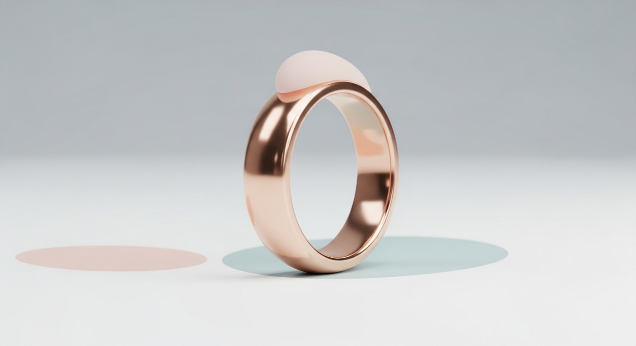 Cincin emas dengan rona merah jambu yang diletakkan di atas permukaan putih.