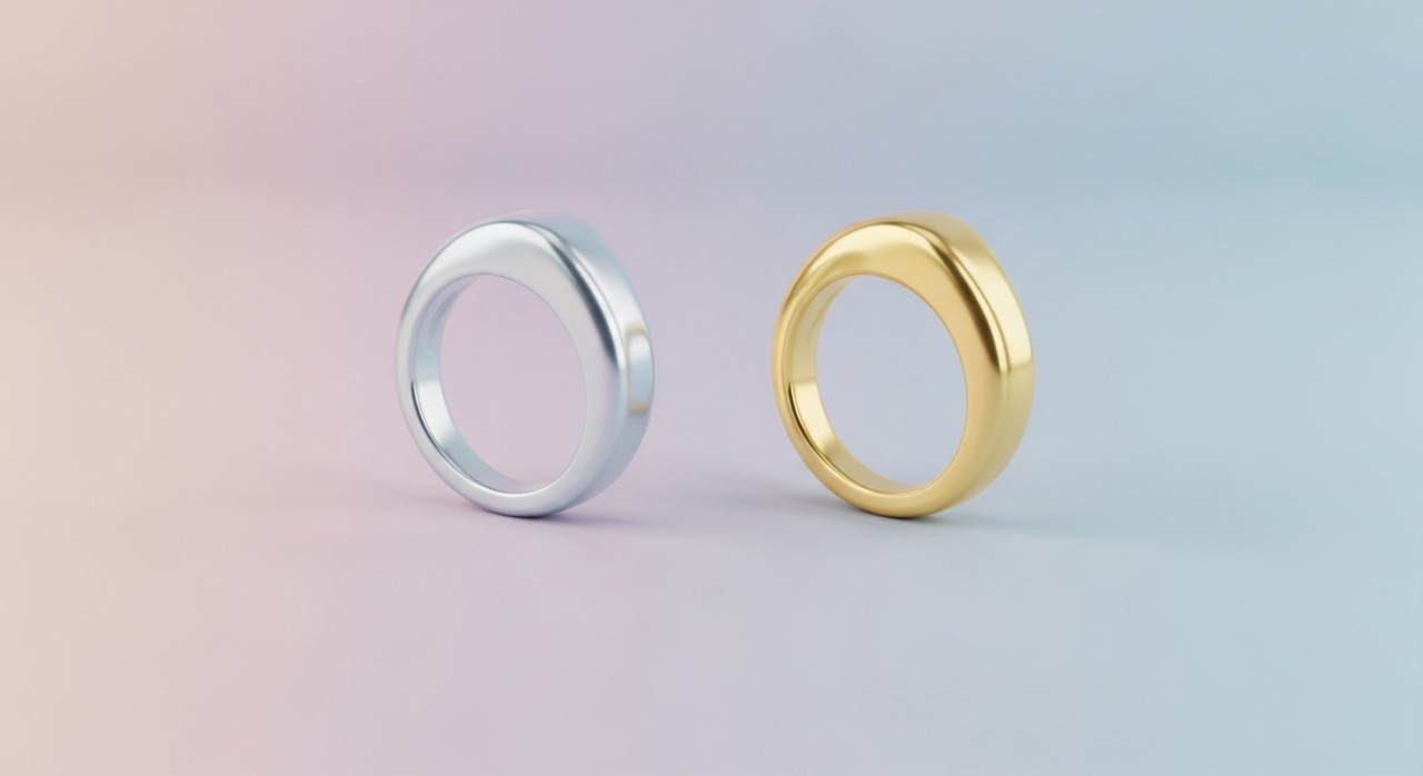 Dua bentuk cincin emas putih dan emas kuning diletakkan secara bersebelahan.